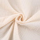 Crèmekleurige katoenen mousseline stof, close-up textuur, zachte en ademende stof, ideaal voor babykleding en zomerkleding.