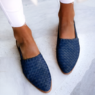 Donkerblauwe gevlochten leren damesschoenen, stijlvolle instappers, gedragen op een marmeren vloer. Perfect voor casual en formele gelegenheden.
