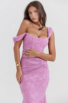 Vrouw in roze kanten jurk met off-shoulder ontwerp, elegante gouden sieraden, modieuze uitstraling. Perfect voor avondkleding en speciale gelegenheden.