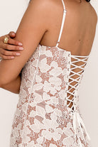 Vrouw in witte kanten jurk met bloemenpatroon en vetersluiting op de rug, elegante zomermode, stijlvolle dameskleding, trendy jurkdetails.